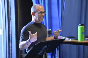 A white man gesticulates at a music stand.