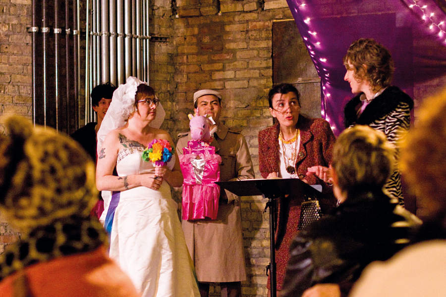 Aunt Tina (Moe Angelos), at podium, presides over the wedding of the bridge (Deb Durham) and groom (Kay Braddock) as a guest (Coman Poon) looks on, in "Let Them Eat Cake," by Angelos, Holly Hughes, and Megan Carney, at New York City's Dixon Place in 2010. (Photo by John W. Sisson Jr.)